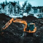 A powerful excavator operates at a Tromsø construction site during winter, showcasing heavy machinery.